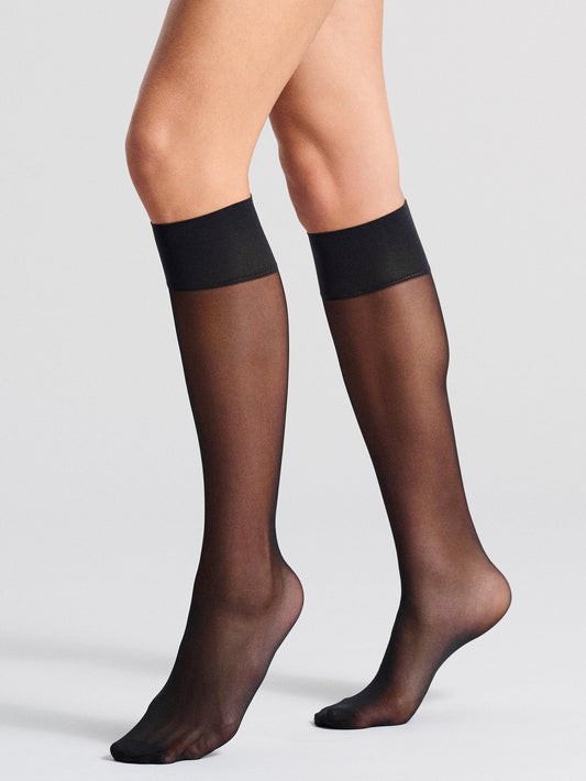 Model showcasing black knee-high socks with reinforced cuffs, giving a glimpse of a sleek, modern style.