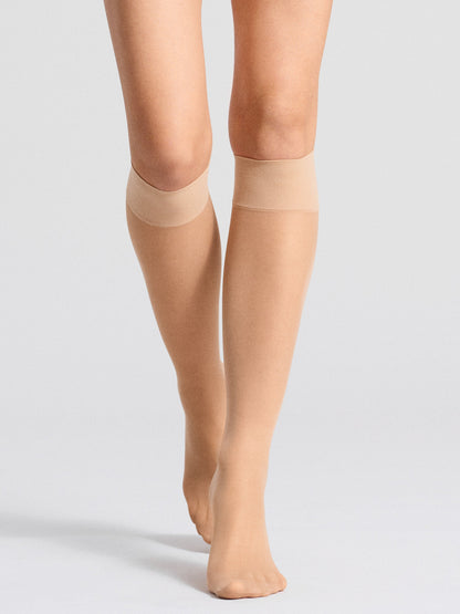 Frontal view of model wearing nude knee-high socks with reinforced cuffs, showcasing a subtle and elegant style.